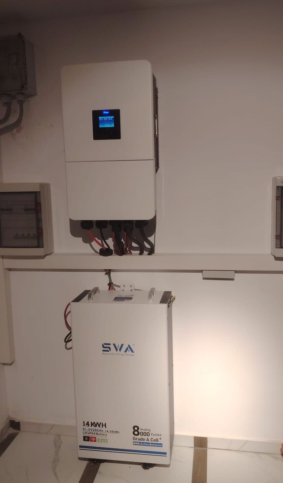 Invertorul hibrid Deye de 20 kW trifazat și bateria SVA de 14 kWh, montate în interior, cu tablourile de protecție de o parte și de alta.